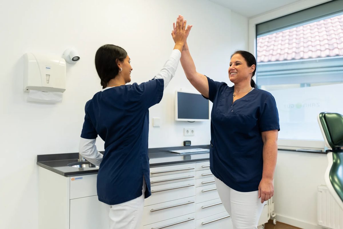 Zwei Kolleginnen klatschen sich im Behandlungszimmer ab